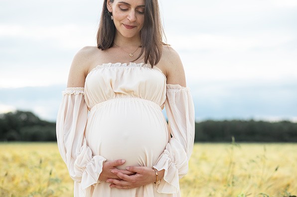 Photographe famille grossesse dijon femme enceinte se tient le ventre dans un champ de blé