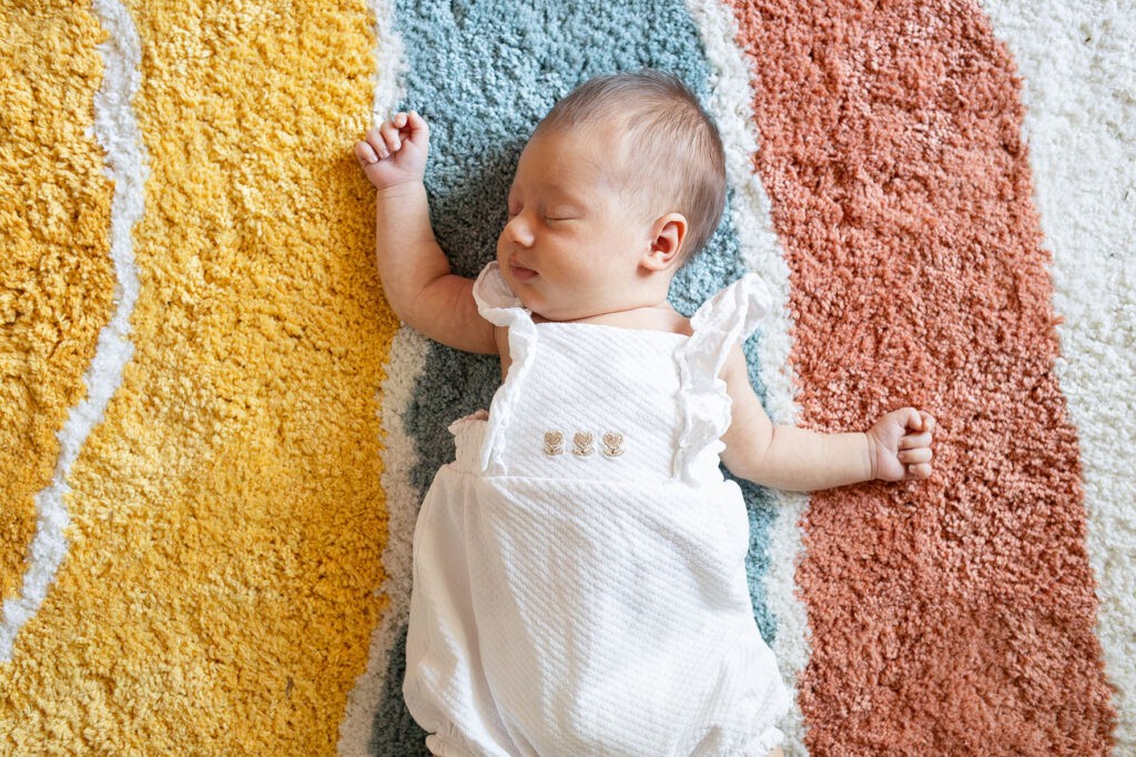 Photographe naissance bebe graphique sur tapis arc en ciel